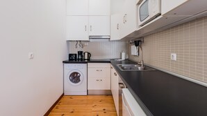 Una cucina compatta con lavatrice, forno a microonde e lavandino.