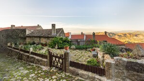 Ein Innenhof mit Steinmauern, einem Holztor und Kübelpflanzen.