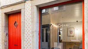 Ein Gebäude mit einer roten Tür und einem großen Fenster voller Blumentöpfe.