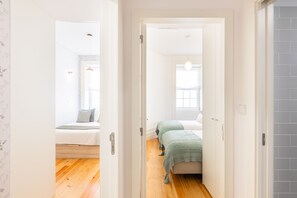 A hallway leading to a bedroom with a bed, a bedside table, and a window. - Apartment Bonfim Perfect Stays (Porto)