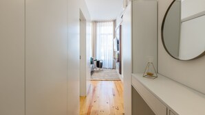 A narrow hallway with wooden flooring, a white wall, and a large mirror. - Santa Catarina Prime Studios (Porto)