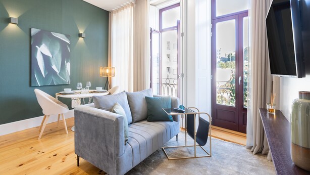 A modern living room with a grey sofa, a small round table, and a flat-screen TV. - Santa Catarina Prime Studios (Porto)
