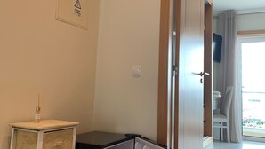 A compact room with a small refrigerator, a bedside table, and a door leading to a balcony. - Apartment Oasis Praia Carvoeiro Bay (Lagoa)