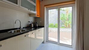 A modern kitchen with a black countertop, stainless steel sink, and white cabinets. - Apartment Oasis Praia Carvoeiro Bay (Lagoa)