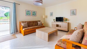 Un salon moderne avec un canapé, une table basse, un téléviseur et des objets décoratifs.