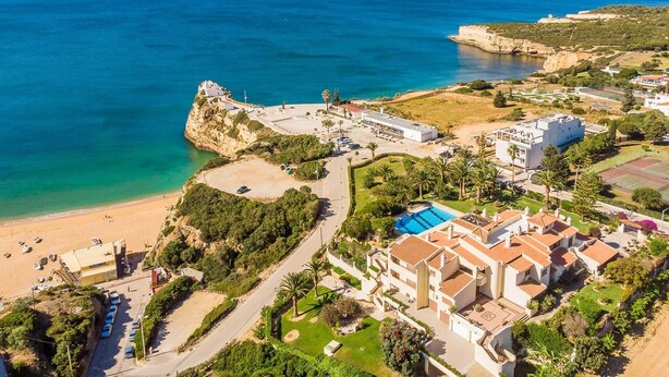 An aerial view of a coastal area with a beach, a fortified structure, and residential buildings. - Quinta das Palmeiras Pool & Beach in Pêra (Lagoa)