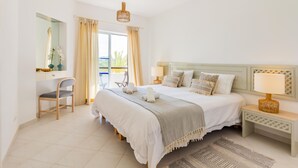A hotel room with a large bed, a desk with a chair, a mirror, and a window with curtains. - Clube Albufeira, Family Holidays with Pool View (Albufeira)