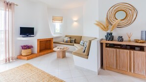 A modern living room with a sofa, a coffee table, a fireplace, a TV, and a decorative wall piece. - Clube Albufeira, Family Holidays with Pool View (Albufeira)