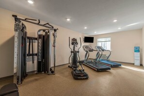 A gym with cardio machines, weight training equipment, and a water dispenser. - WoodSpring Suites Jacksonville - South (Jacksonville)