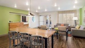 Una sala de estar moderna con una mesa de comedor de madera, sillas grises, un sofá y una mesa auxiliar.