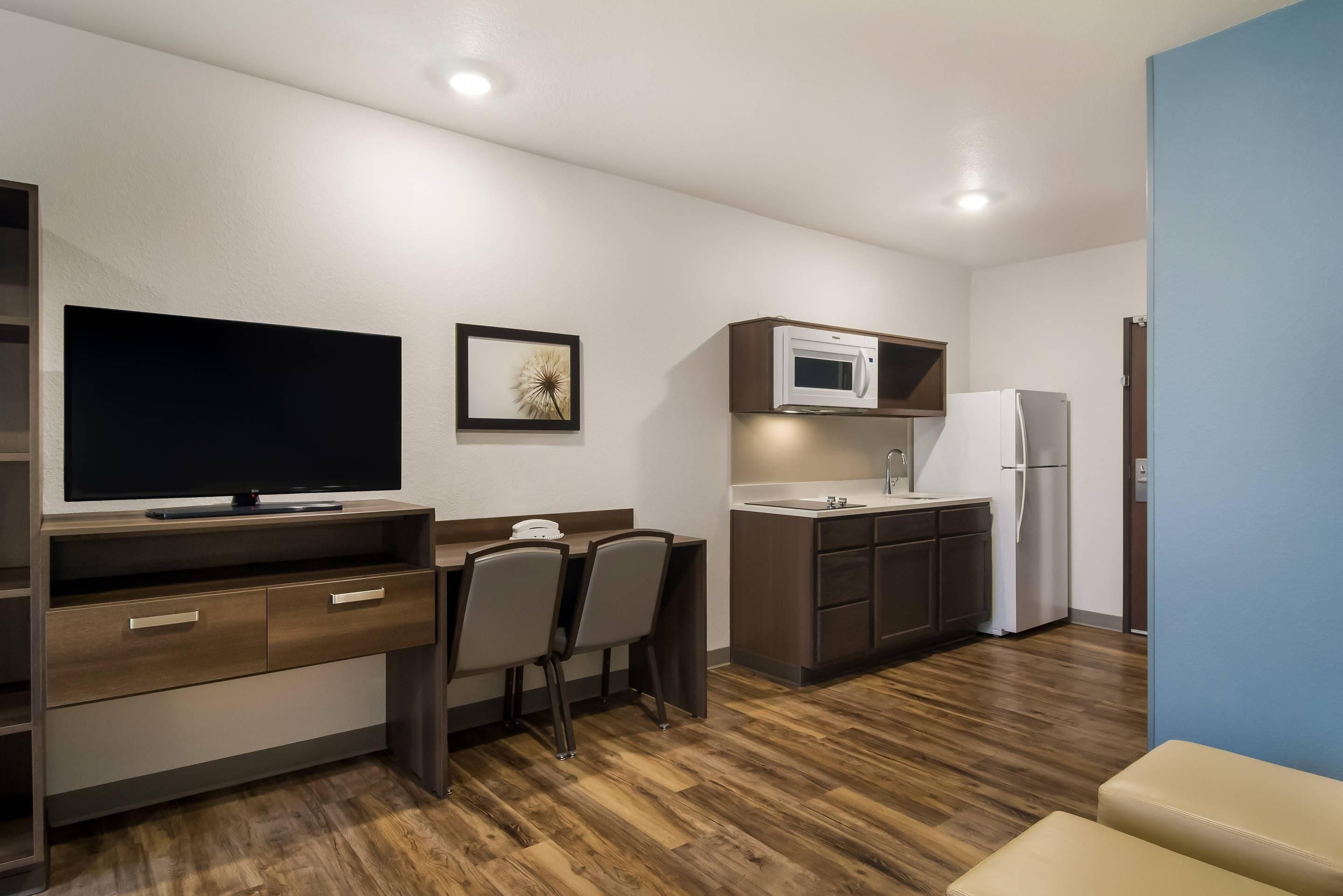 Una kitchenette compacta con microondas, refrigerador y televisor de pantalla plana.