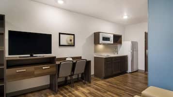 Una kitchenette compacta con microondas, refrigerador y televisor de pantalla plana.