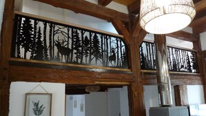 A rustic interior with wooden beams, a fireplace, and a forest-themed wall panel.