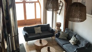 A cozy living room with a fireplace, two sofas, and a large window.