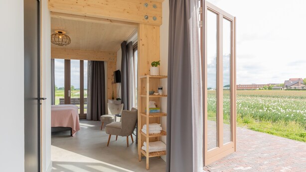 Ein modernes Interieur mit einem Bett, einer Sitzecke und einem Holzregal mit Handtüchern.