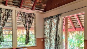 Una habitación con techo de madera, una cama, un banco y una ventana con cortinas.