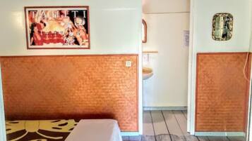 Een hotelkamer met een bed, een kleine badkamer en een houten vloer.