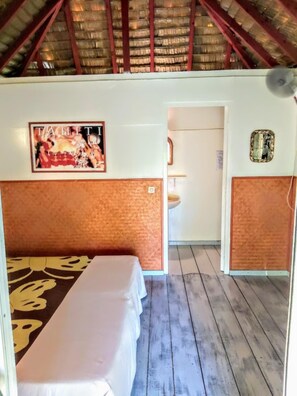Ein Hotelzimmer mit Bett, einem kleinen Badezimmer und Holzboden.