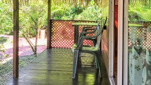 Un espacio al aire libre techado con paja, una mesa con sillas y vista a la vegetación.