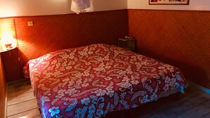 Un dormitorio con una cama cubierta con una colcha de estampado floral, una mesita de noche con una lámpara y una lámpara de pared.