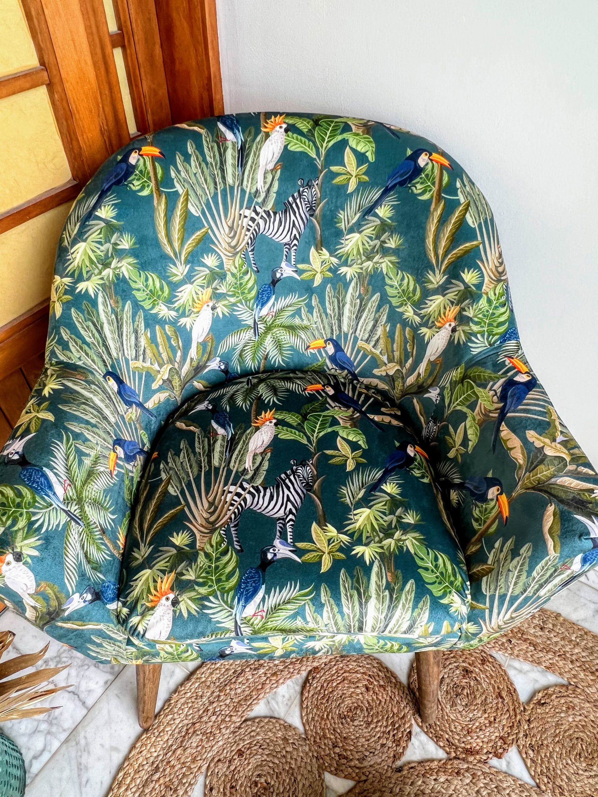 A chair with a vibrant tropical animal print upholstery.
