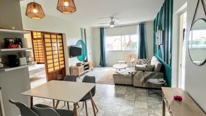 Un salon moderne avec un coin repas, un ensemble de canapés et une cuisine visible au fond.