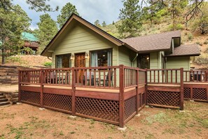 A cabin with a wooden deck, a front door, and windows. - Hot tub ☆ Fire-pit ☆ Walk to Waterfalls (Green Mountain Falls)