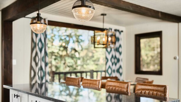 Una cocina con isla central, luces colgantes y vistas al exterior.