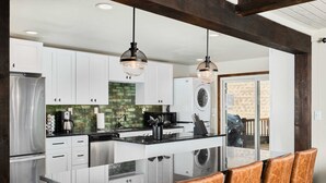 Una cocina moderna con gabinetes blancos, una isla central e iluminación colgante.