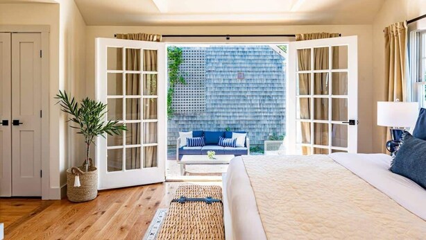 A bedroom with a large bed, a sofa, and a view of the outside. - Luxurious Nantucket Getaway | Heated Pool (Nantucket)