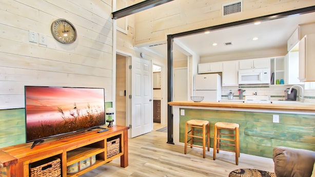 Una sala de estar moderna con un mueble bajo de televisión de madera, un televisor plano grande, una mesa de centro de madera y un sofá cómodo.