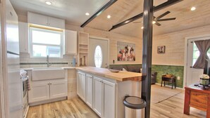 Una cocina con armarios blancos, encimera de madera y una ventana.