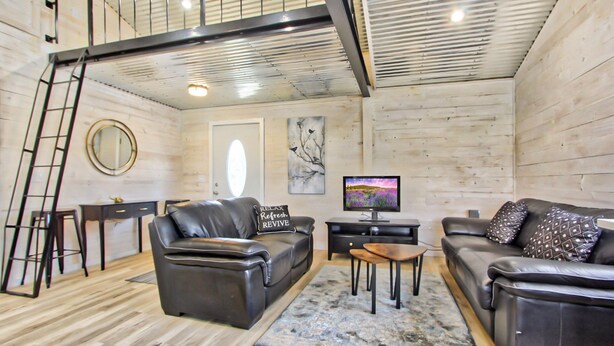 Un salon moderne avec deux canapés en cuir, une table basse, un téléviseur et un escalier.