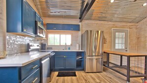 Une cuisine moderne avec des meubles bleus, des appareils en acier inoxydable et un plancher en bois.