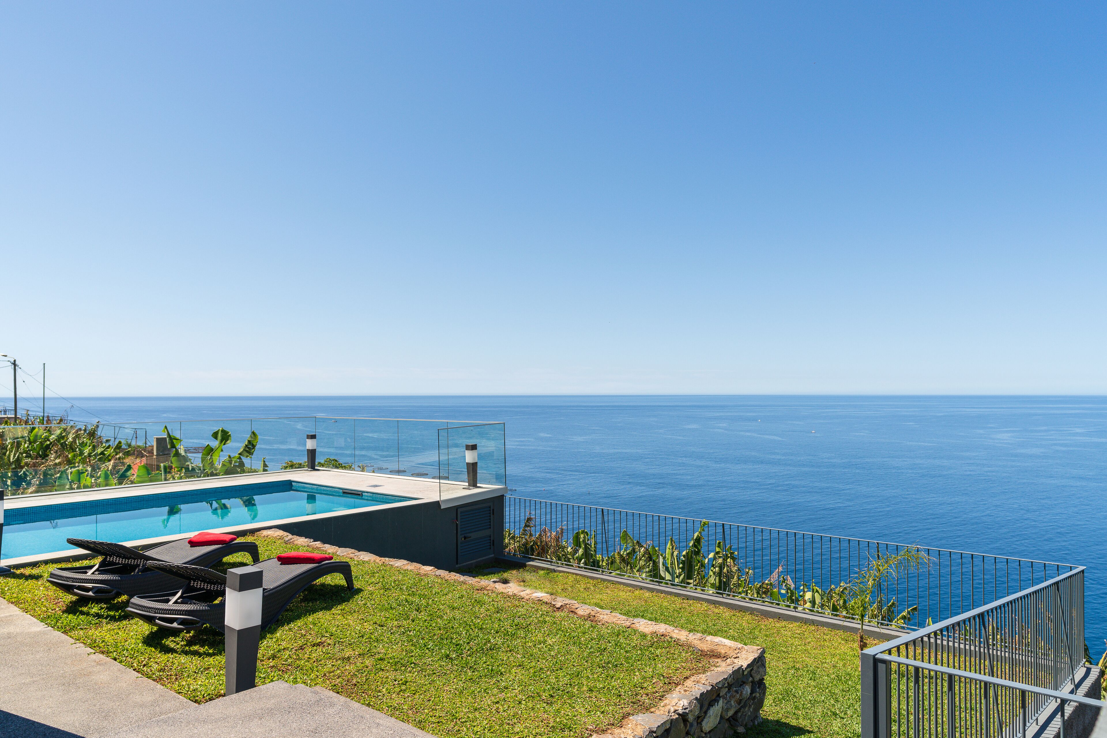 A swimming pool with lounge chairs and a view of the ocean.