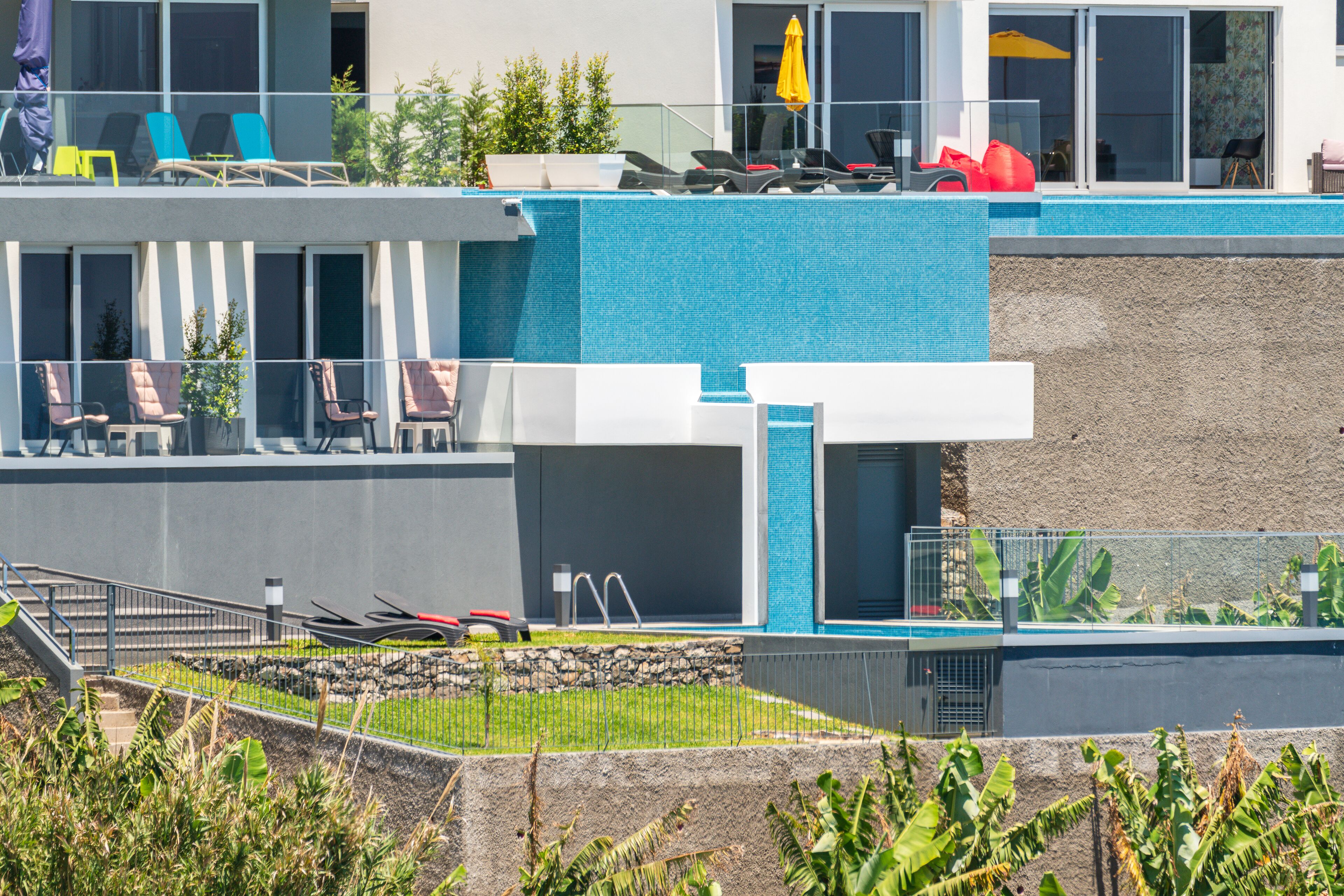 A modern hotel with a pool area, outdoor seating, and a staircase leading to the upper level.