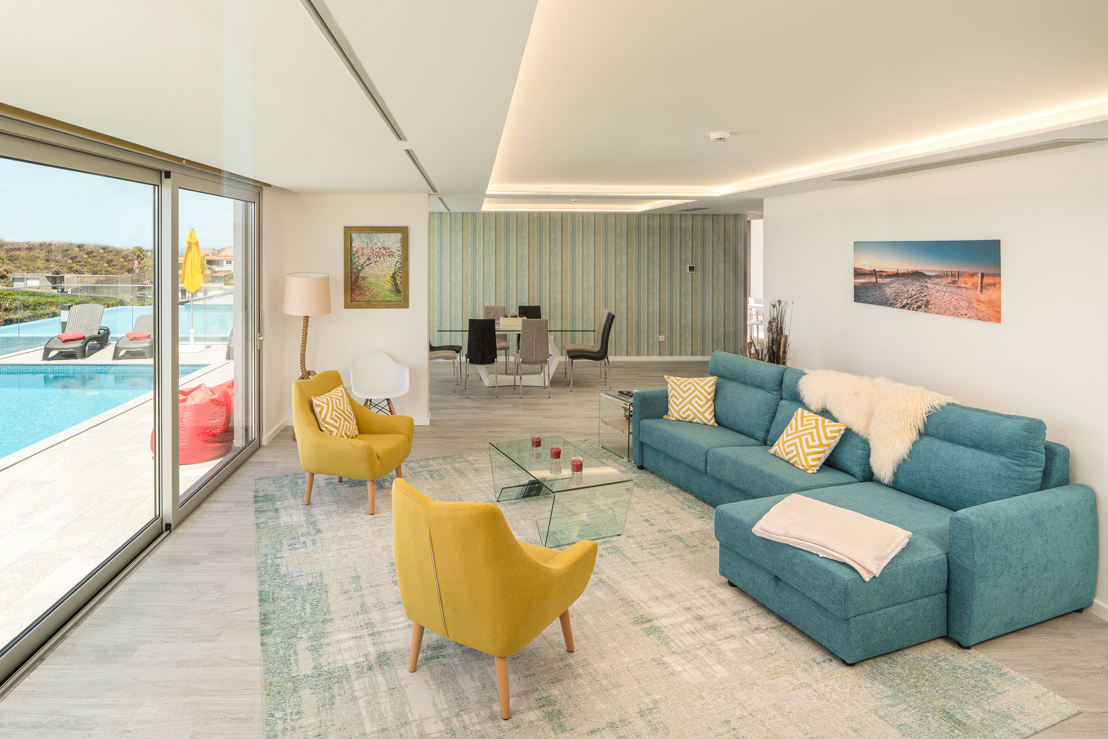 A modern living room with a sofa, armchairs, and a glass coffee table.