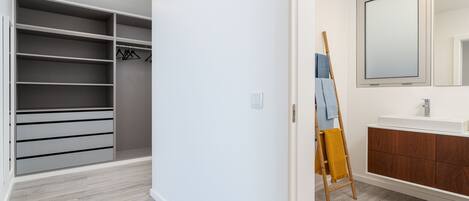 A modern bathroom with a large mirror, a wooden ladder, and a white vanity.