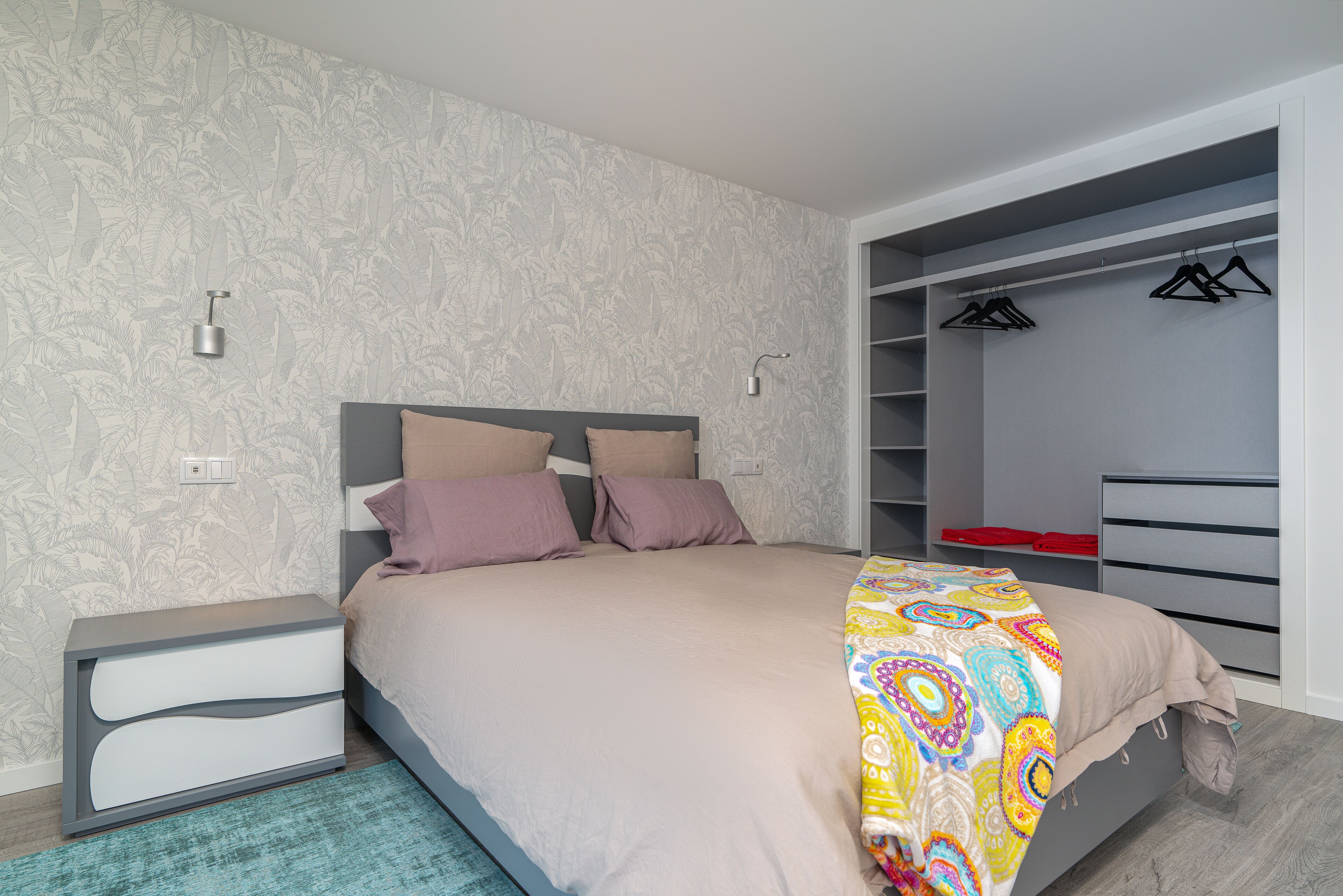 Quarto com cama, mesas de cabeceira, guarda-roupa e armário.
