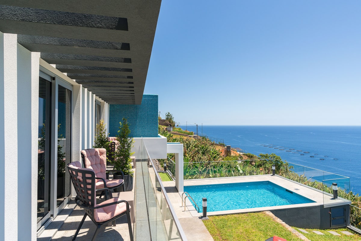 Ein Balkon mit Pool, Stühlen und Blick aufs Meer.