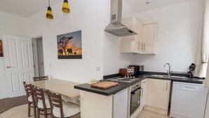 A compact kitchen with a dining area, featuring a central island, a stove, a dishwasher, and a sink.