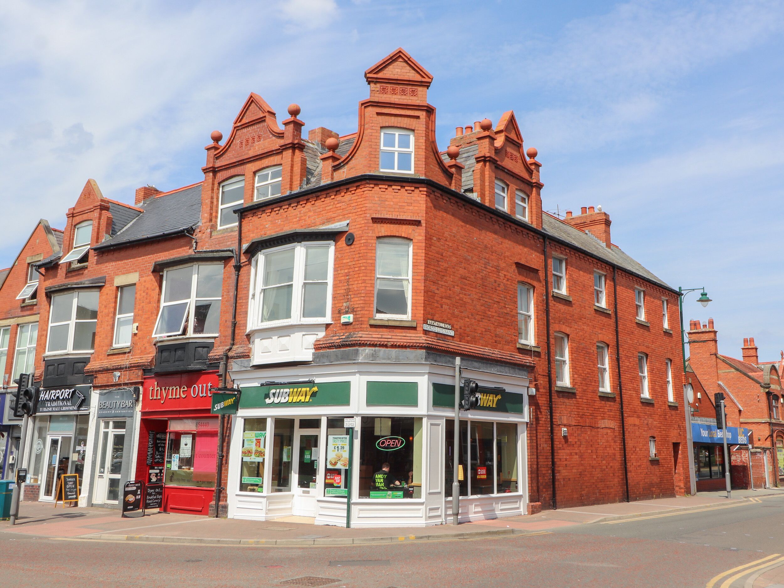 A corner building with a Subway restaurant, a beauty salon, and a traditional hair salon.
