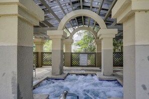 Un espace avec un bain à remous offrant une vue sur les arbres, ainsi qu’un panneau d’avertissement.