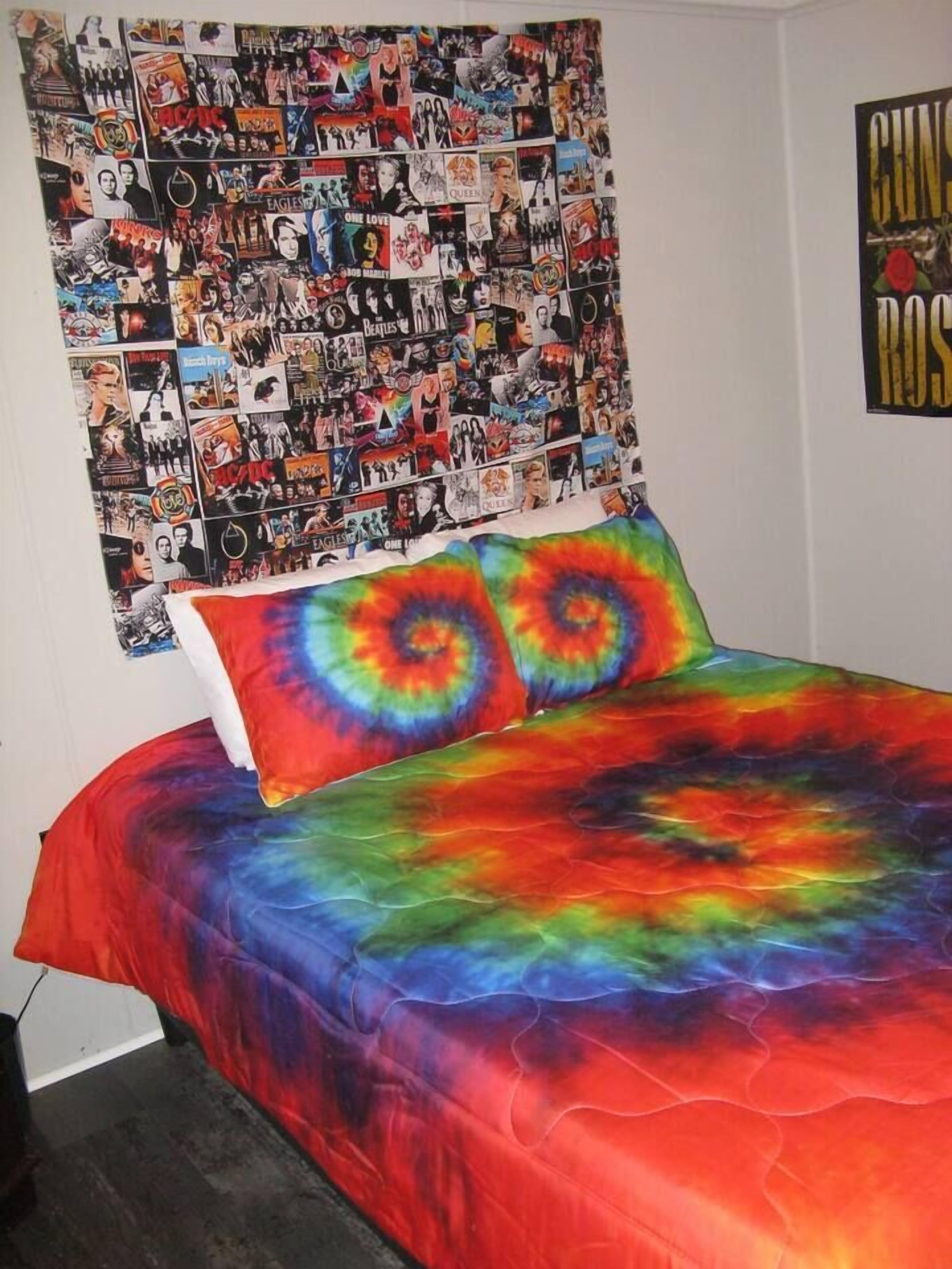 Un dormitorio con una colcha de tonos vibrantes estilo tie-dye, un tapiz de pared con varios carteles, y un cartel de Guns N' Roses en la pared.