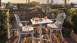 A balcony with two white chairs and a table set for two, overlooking a cityscape with historic buildings. - Eurostars Florence Boutique (Florence)