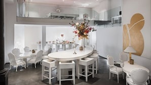 A modern dining area with white furniture, a central round table, and a decorative floral arrangement. - Eurostars Florence Boutique (Florence)