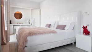 A modern bedroom with a large bed, bedside tables, a round mirror, and a red dog figurine. - Eurostars Florence Boutique (Florence)
