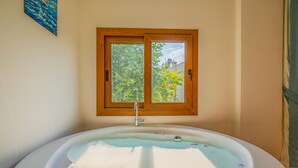 A bathroom with a bathtub, a window, and a painting on the wall. - Myra Villa 1 (Fethiye)