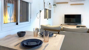 Una sala de estar moderna con una mesa de comedor, sofá, televisor y una lámpara colgante.
