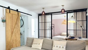 Una sala de estar moderna con sofá, puerta corredera de madera y un amplio ventanal con cortinas.
